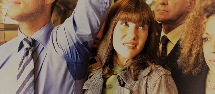 Closeup of a female commuter standing by man's wet armpit in a c